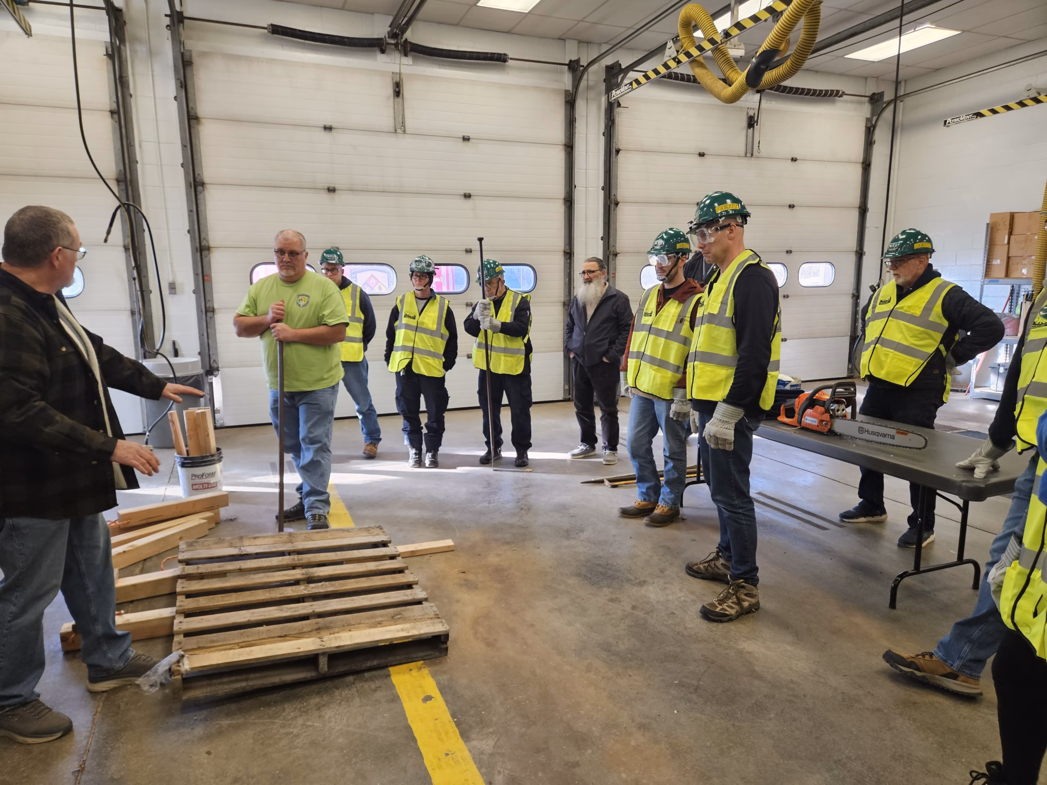The class gathers around cribbing practice in the apparatus bay