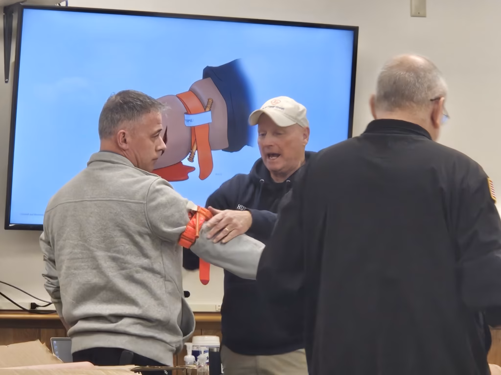 Instructors practise applying a tourniquet in front of the class