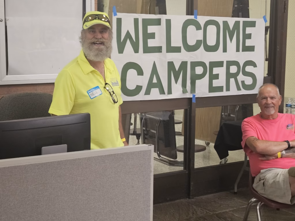 A CERT volunteer beside a Welcome Campers sign at the exercise